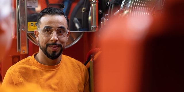 Ein Mann mit Schutzbrille vor einer großen Maschine in einer industriellen Umgebung